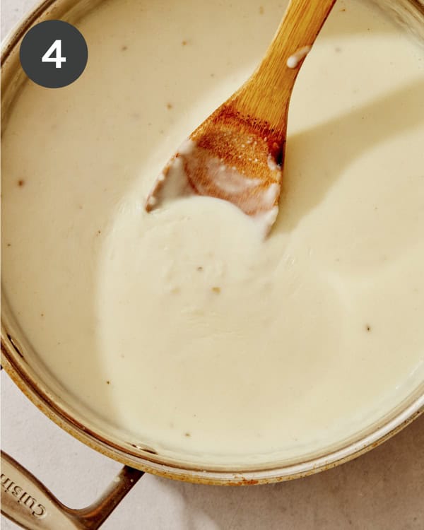 A creamy sauce simmering in a skillet to make green bean casserole.