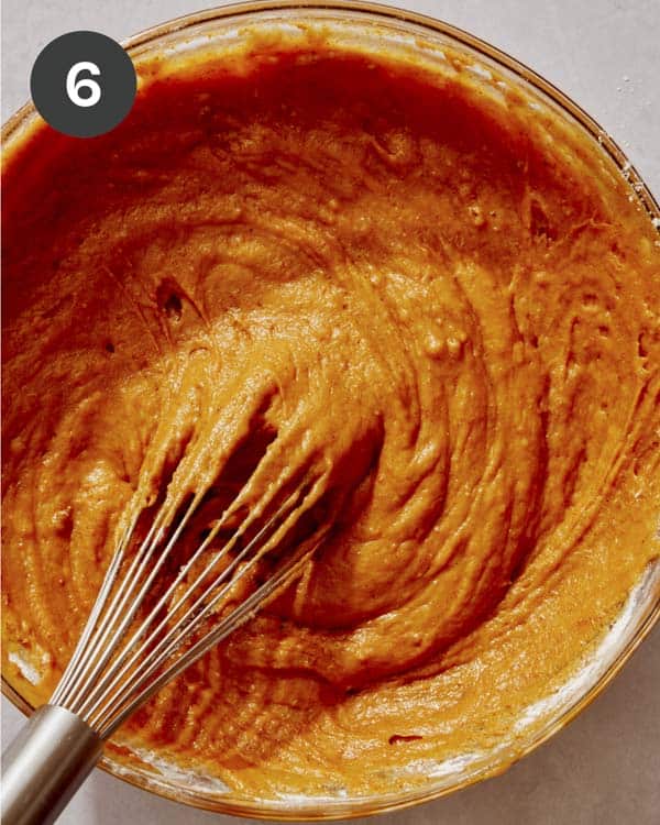 Pumpkin cake batter being mixed together in a glass bowl.