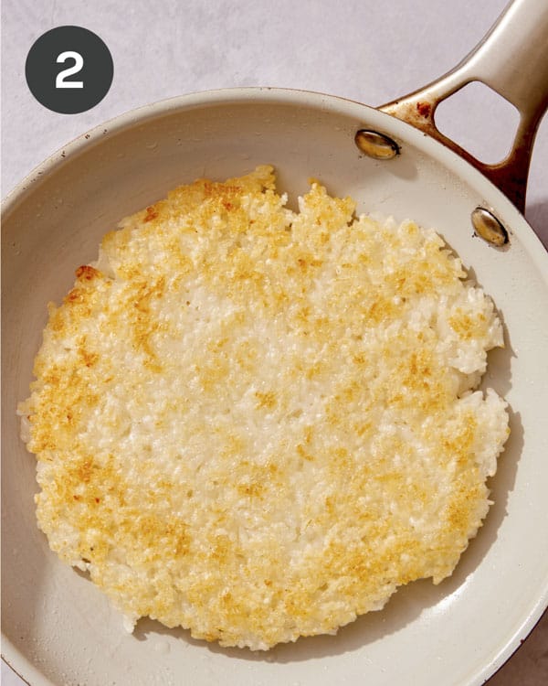 Golden brown rice in a skillet being cooked.
