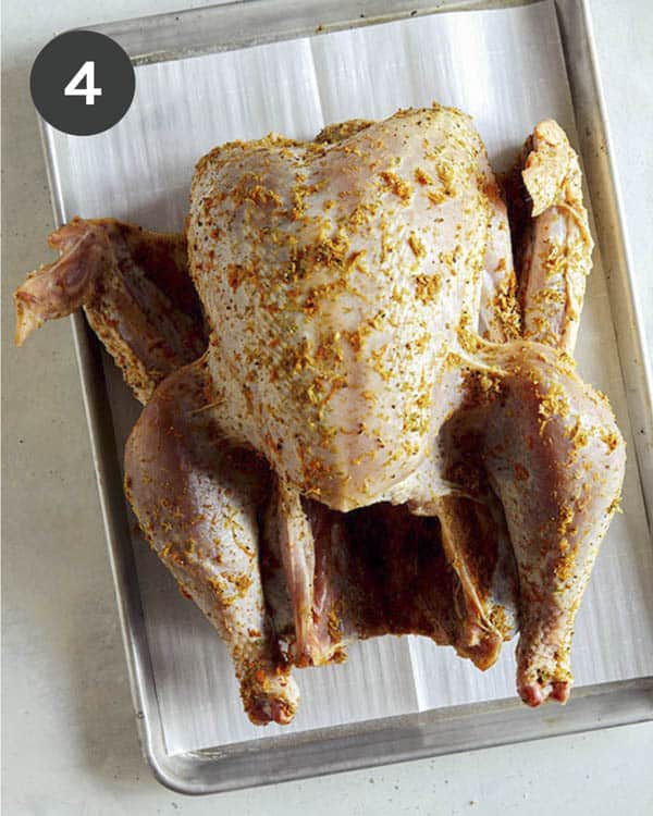 A turkey on a baking sheet rubbed with a citrus dry brine.