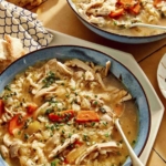 Chicken and rice soup recipe served in two bowls with a spoon in one.