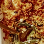 Close up on a green bean casserole with a serving taken out of it.
