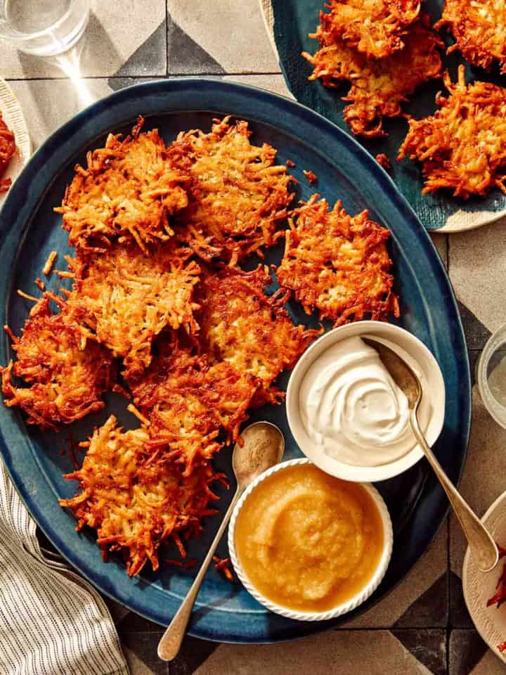 Potato latkes on a platter with applesauce and sour cream.