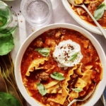 Lasagna soup recipe in a bowl with basil on the side.