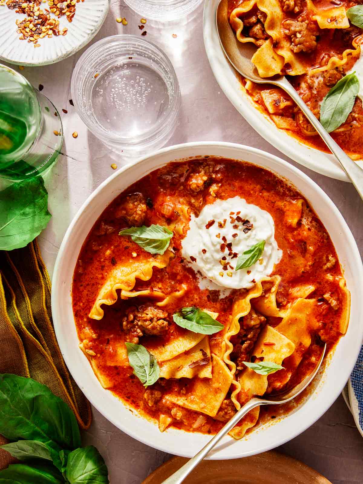 Lasagna soup recipe in a bowl with basil on the side. 