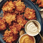 Potato latkes on a platter with applesauce and sour cream.