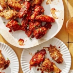 Korean fried chicken being served onto plates.