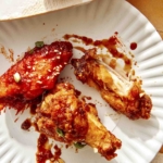 Korean fried chicken on a plate being eaten.