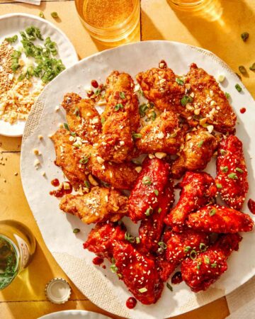 Korean fried chicken on a platter with garnishes on the side.