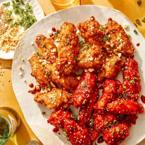 Korean fried chicken on a platter with garnishes on the side.