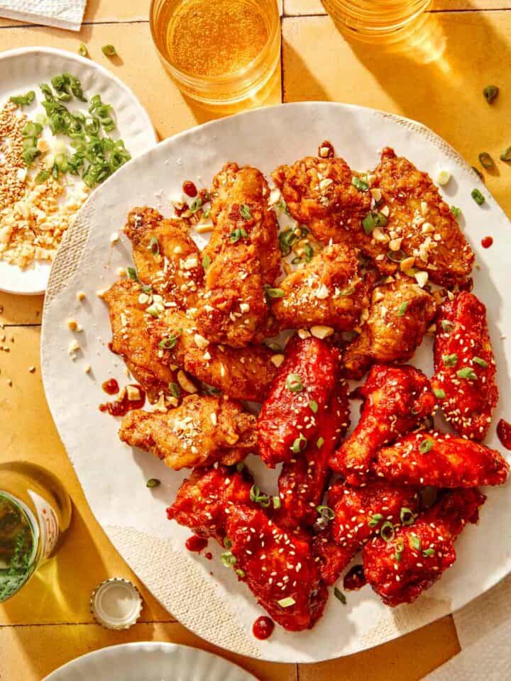 Korean fried chicken on a platter with garnishes on the side.
