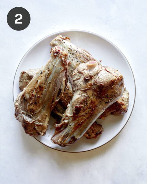Seared lamb shanks on a plate.