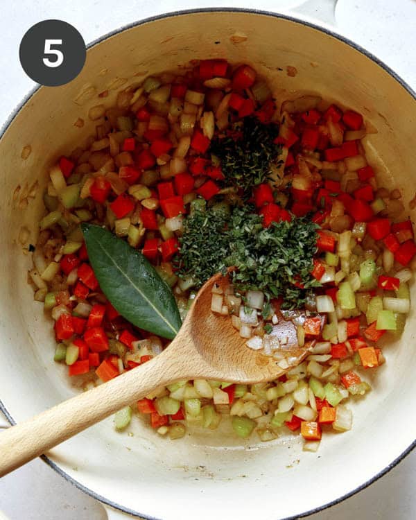 Veggies and herbs in a stock pot to make braised lamb shanks.