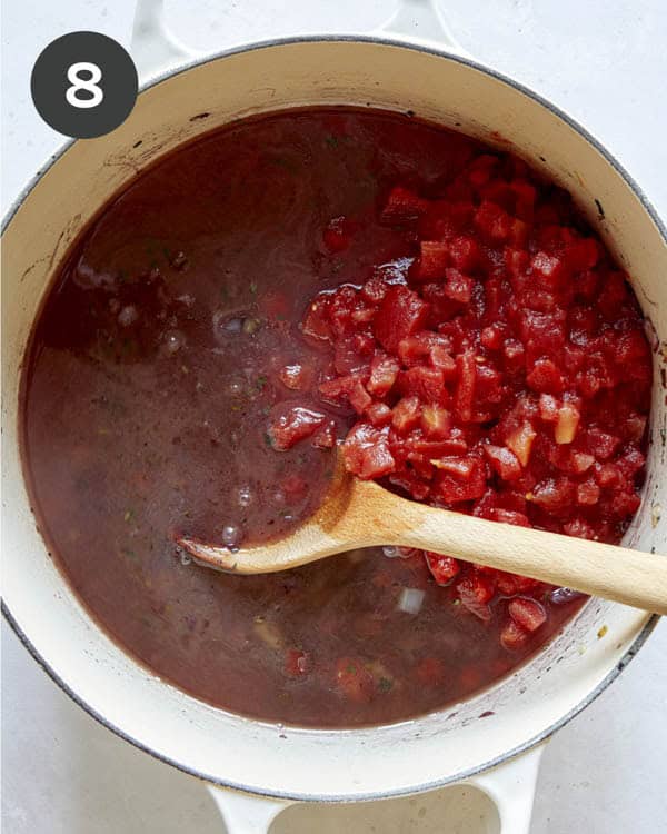 Tomatoes and stock in a pot to make braised lamb shanks.