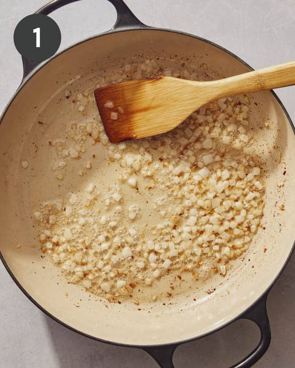 Cooking onions in a skillet to make a chopped cheese sandwich.