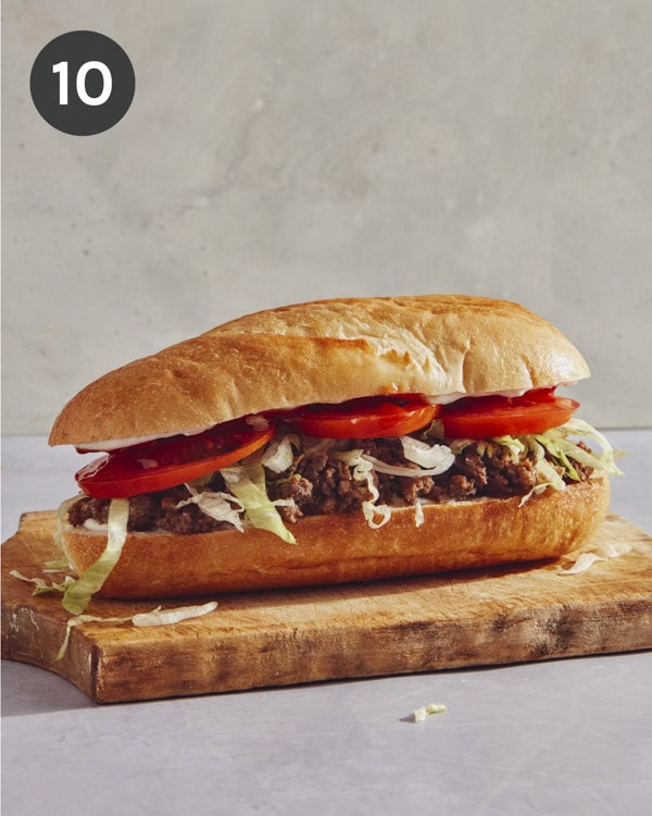 A whole chopped cheese sandwich on a cutting board.