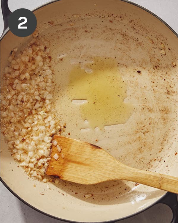 Onions pushed to the side in a skillet.