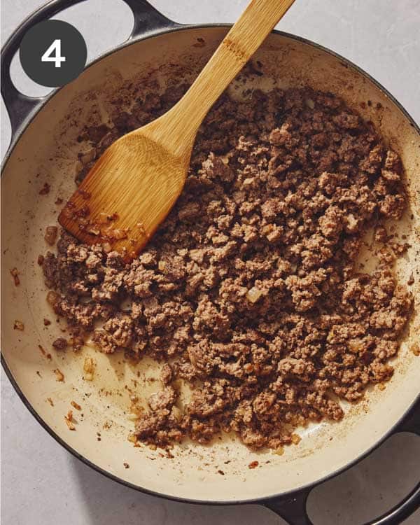 Chopped up hamburger patties in a skillet with onions.