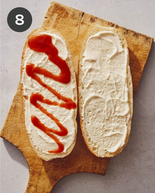 A hero roll with mayonnaise and ketchup on it.