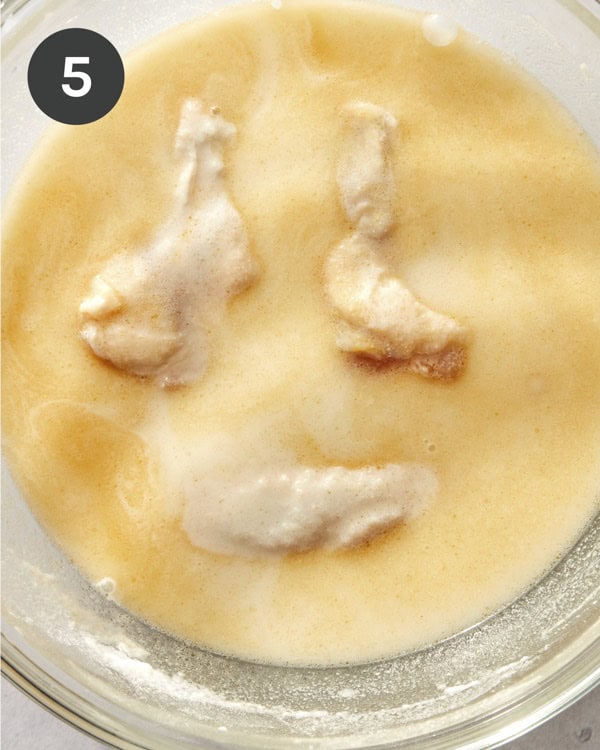 Chicken being tossed in a batter to make fried chicken.