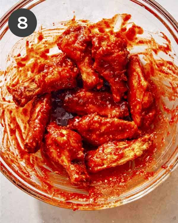 Korean fried chicken being tossed with a spicy sauce. 