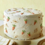 A tall carrot cake on a cake stand.