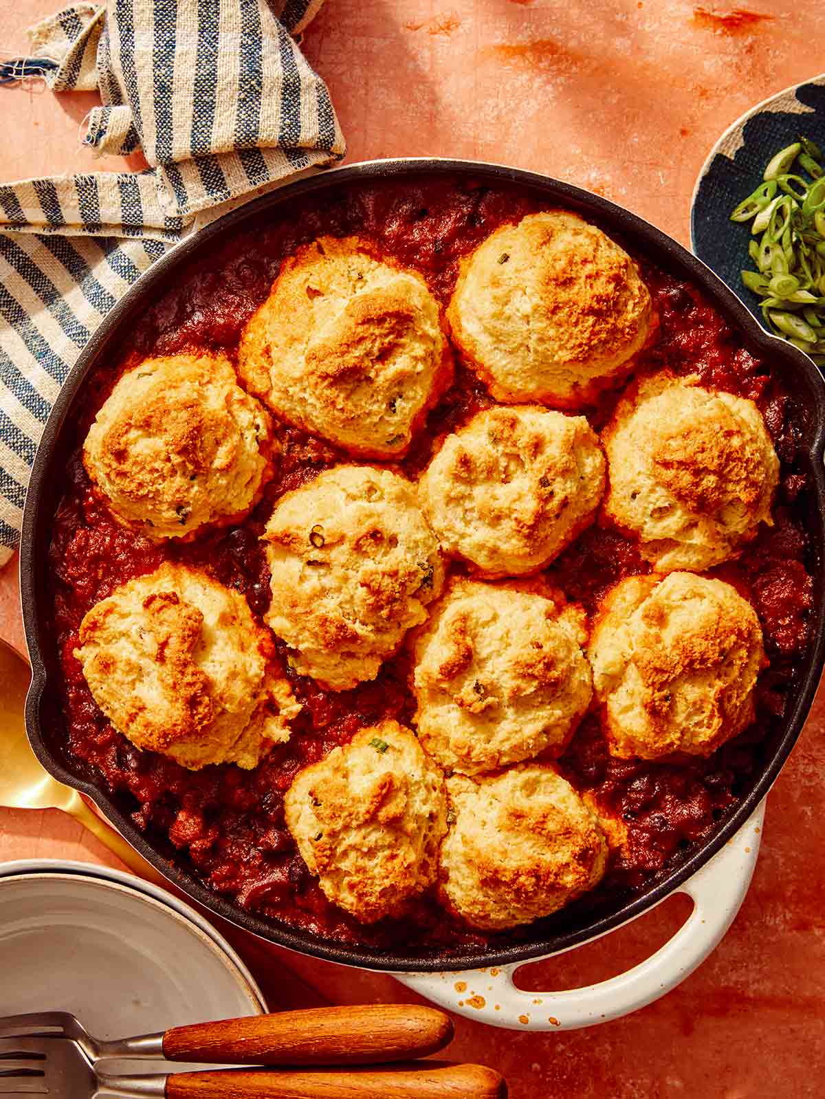 Chili cornbread casserole in a skillet with bowls next to it.