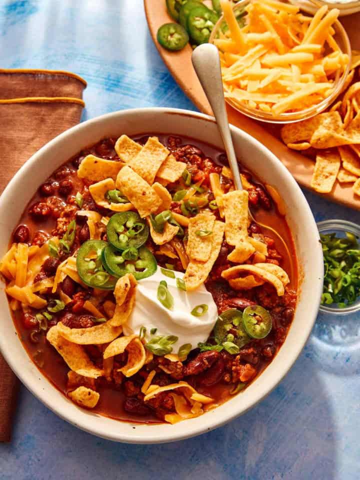 Chili being served in a bowl with toppings on the side.