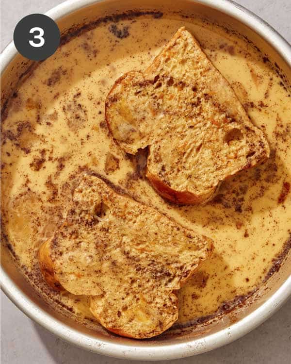 Thick pieces of bread soaking in an egg mixture to make french toast.