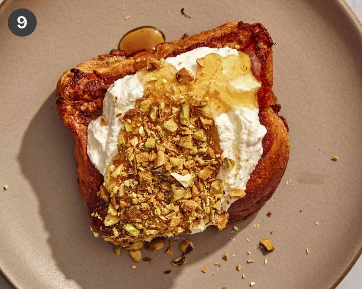 A slice of french toast topped with ricotta, nuts, and honey.