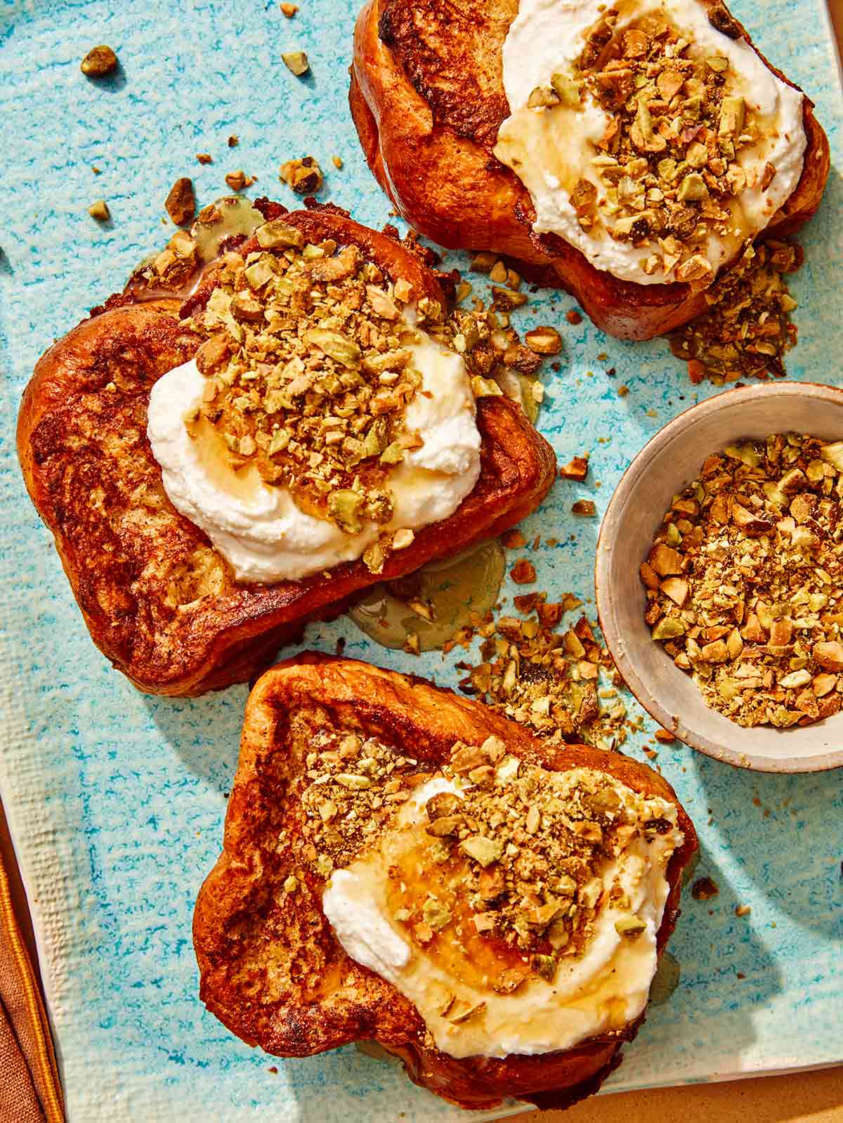 French toast on a platter topped with ricotta and nuts.