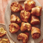 Popovers being served on a platter with a plate next to it with a popover ripped open.