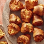 Popovers being served on a platter with a plate next to it with a popover ripped open.