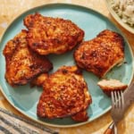 Air fryer chicken thighs on a platter with slice taken out of one.