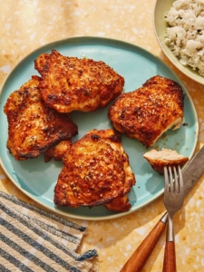 Air fryer chicken thighs on a platter with slice taken out of one.