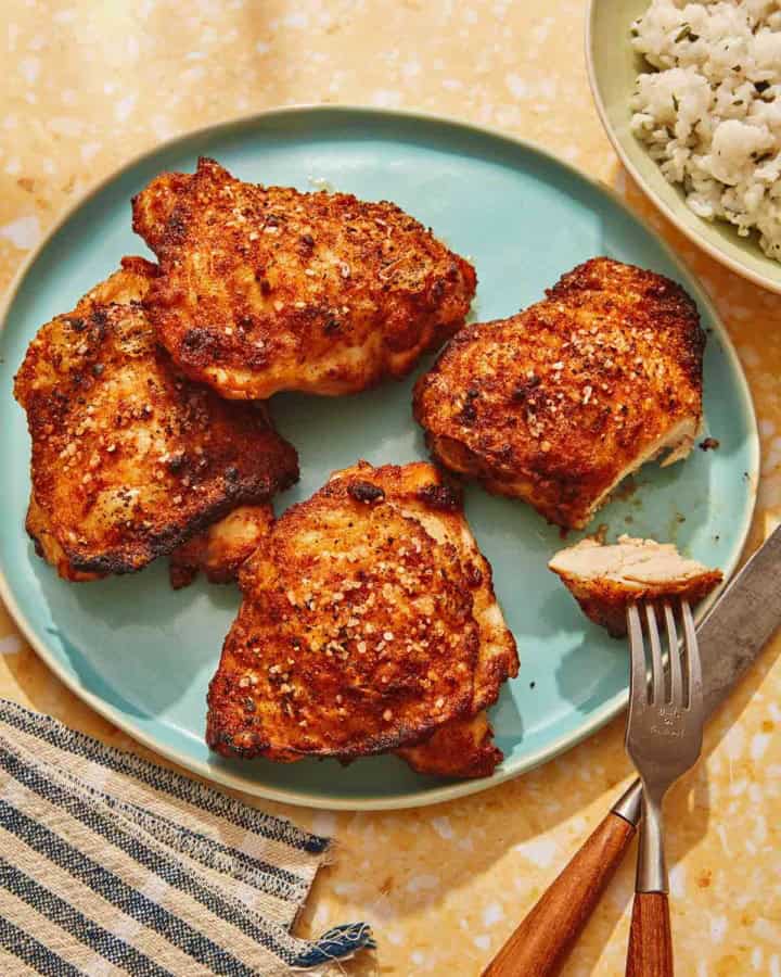 Air fryer chicken thighs on a platter with slice taken out of one.