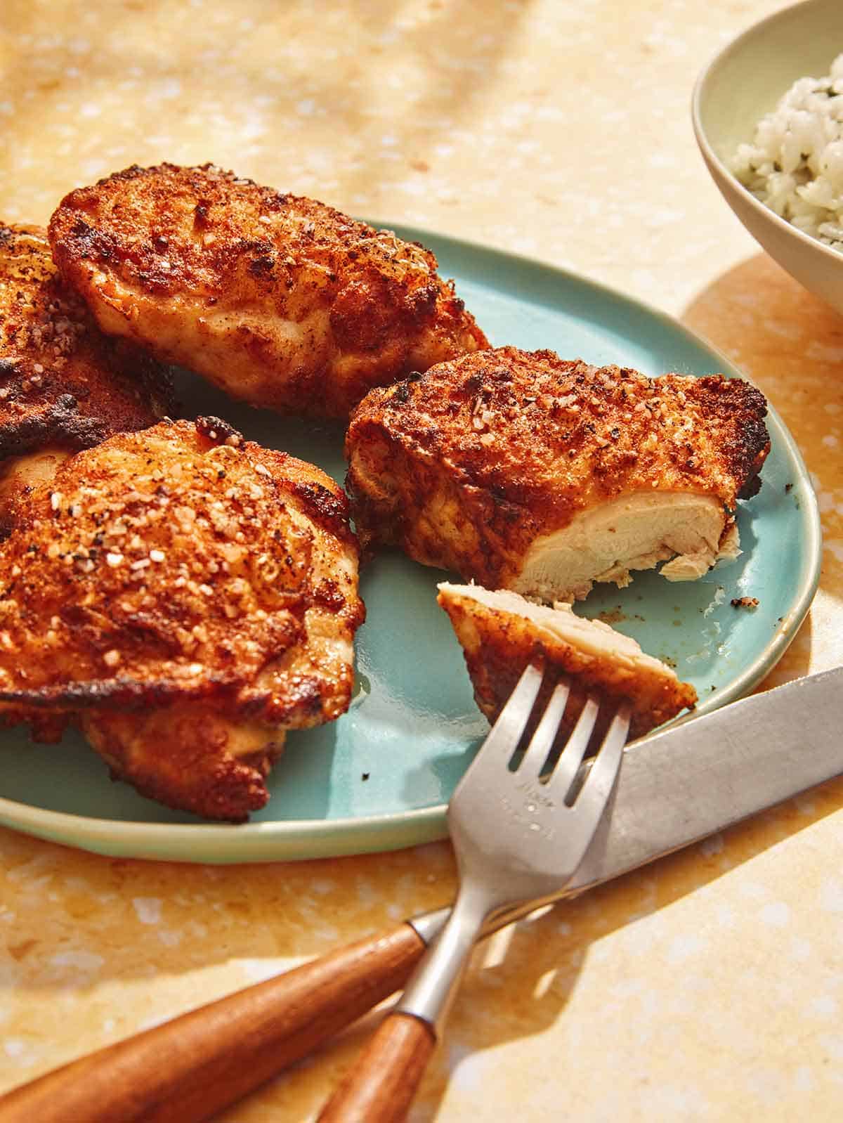 Close up on a platter of chicken thighs with a one cut open.