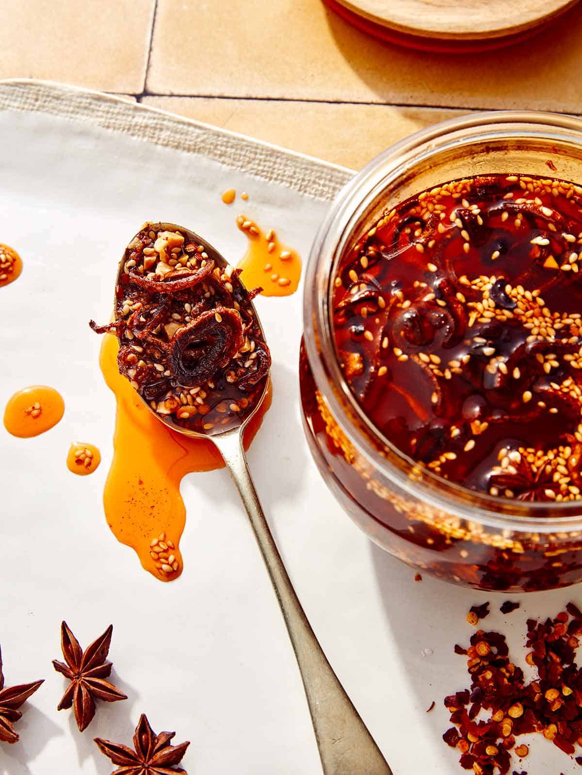 Chili crisp in a jar with a spoon next to it.