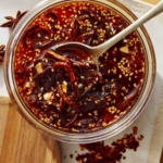 Chili crisp with a spoon taking some out of a jar.