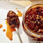Chili crisp in a jar with a spoon next to it.
