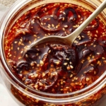 Chili crisp in a jar with a spoon tucked in it.