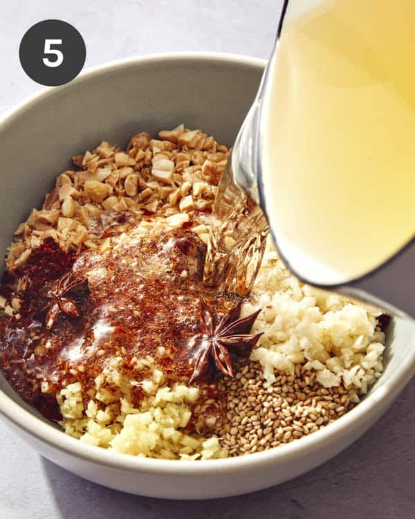 Hot oil being poured onto chili crisp ingredients.