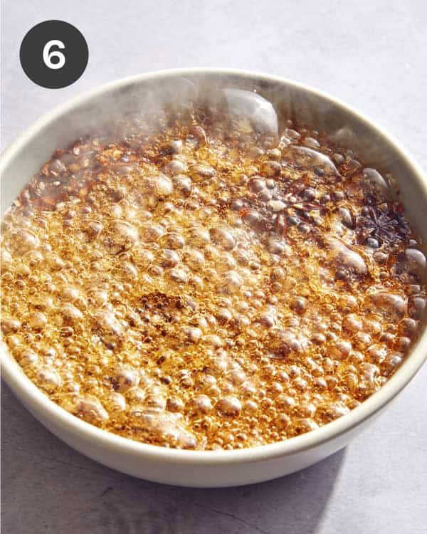 Hot oil bubbling in a bowl to make chili crisp.