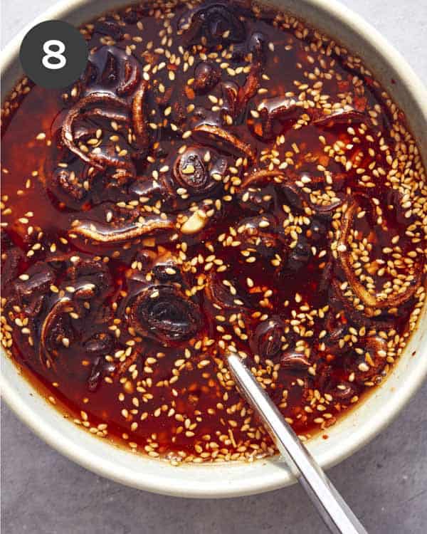Fried shallots being stirred into a bowl of chili crisp.