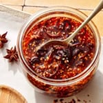 Chili crisp in a jar with a spoon in it.