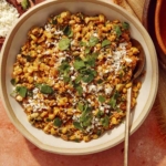 Mexican street corn salad in a bowl with a spoon in it.