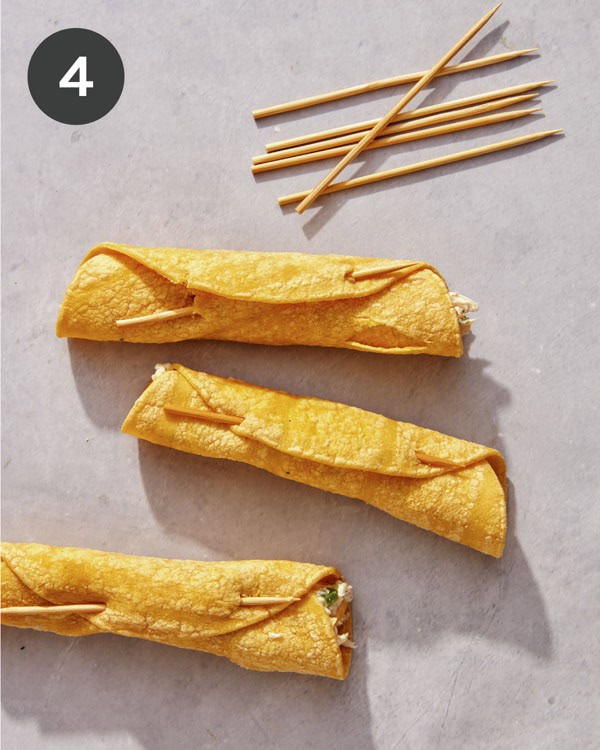 Taquitos rolled up before they are cooked and closed with a toothpick.