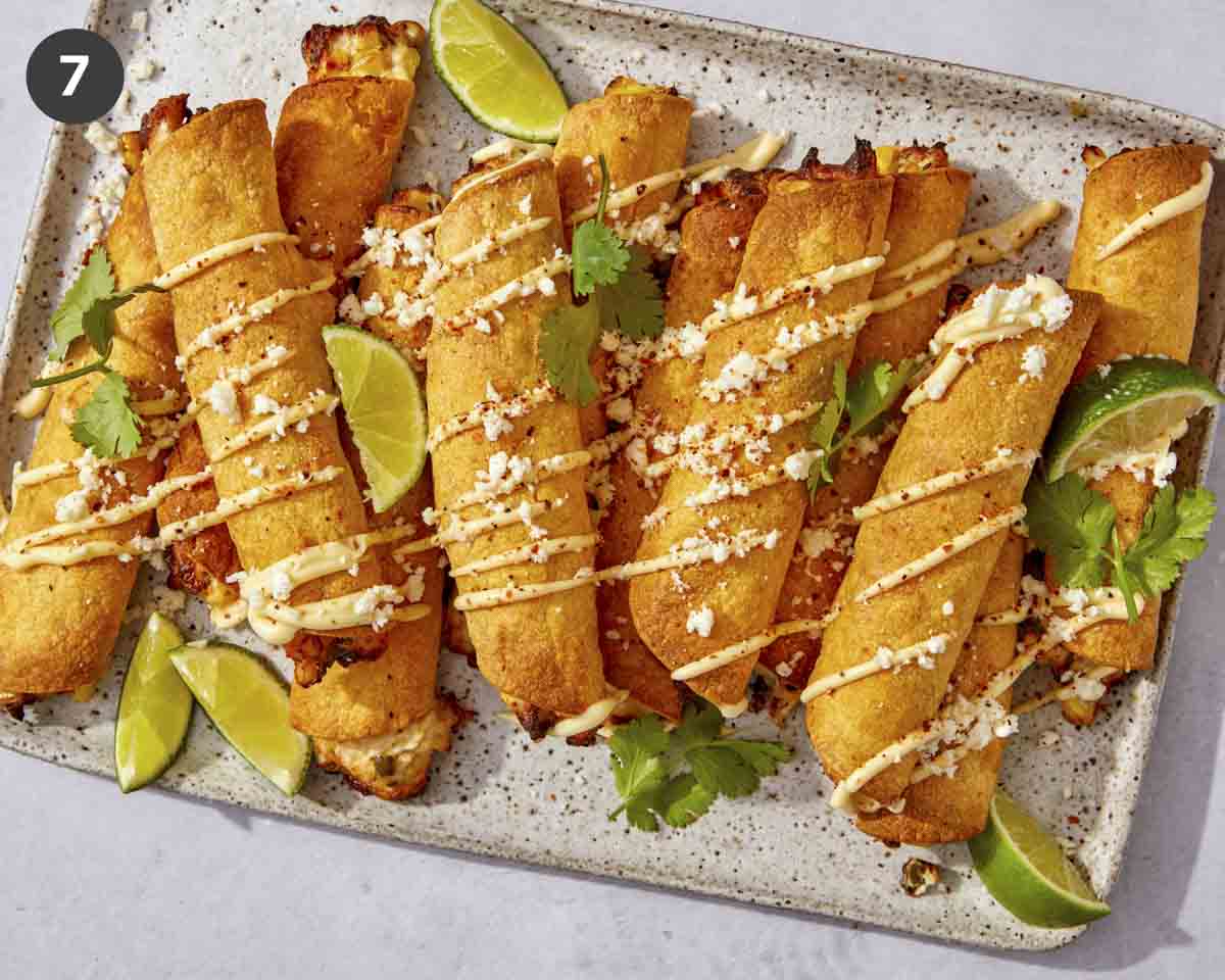 Air fryer taquitos on a platter with toppings.