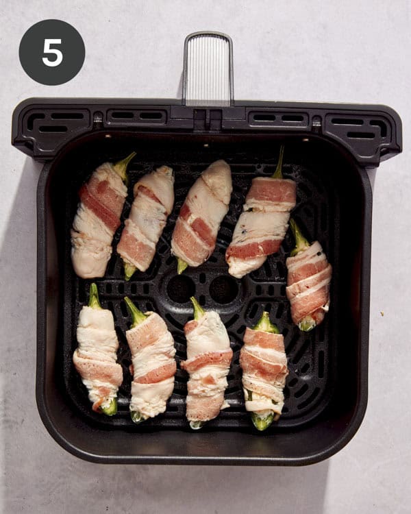 Jalapeno poppers in an air fryer basket.