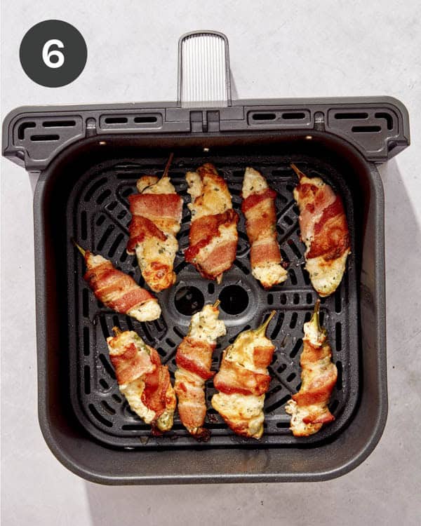 Jalapeno poppers cooked in an air fryer basket.